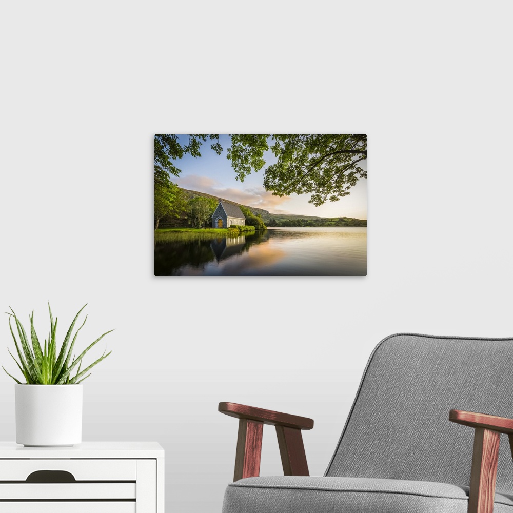 A modern room featuring Old chapel of Gougane Barra situated by a lake and framed by green trees at sunrise; Gougane Barr...