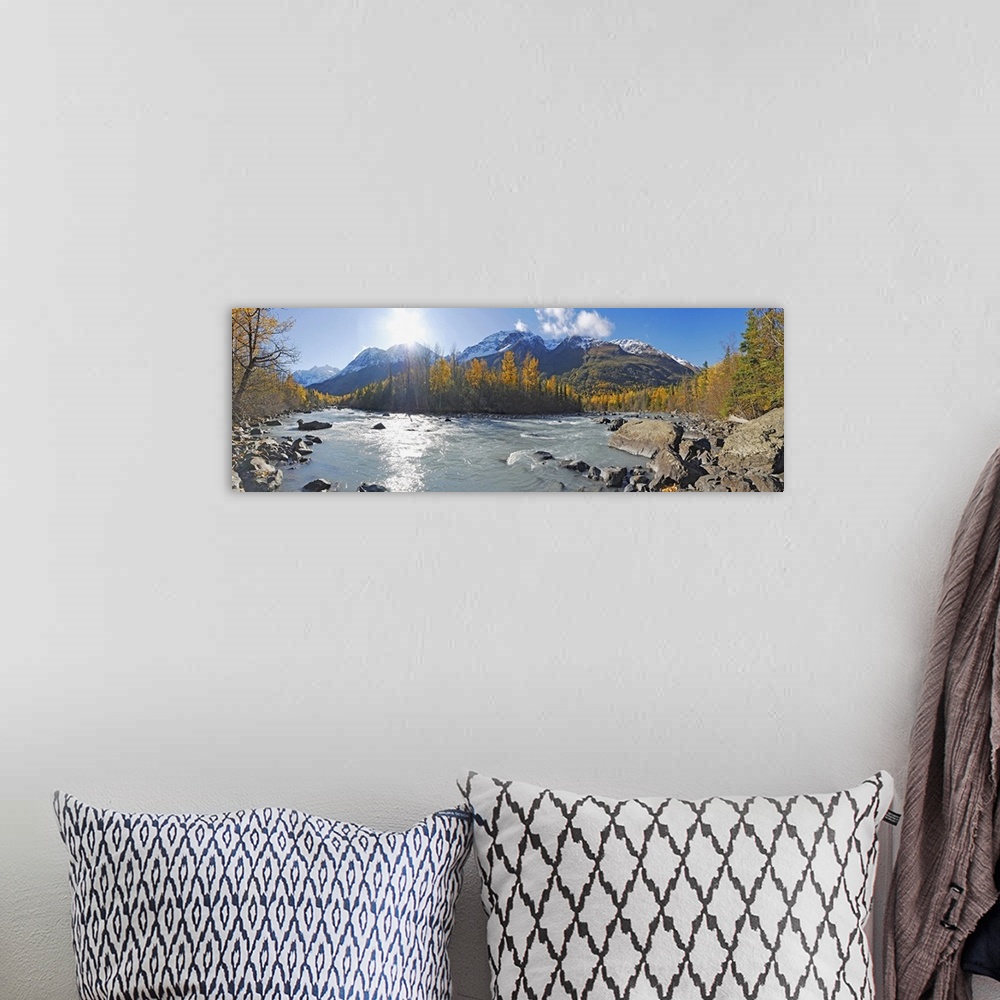 A bohemian room featuring A photograph of a river running through the Alaskan landscape in lined with trees on a sunny day ...