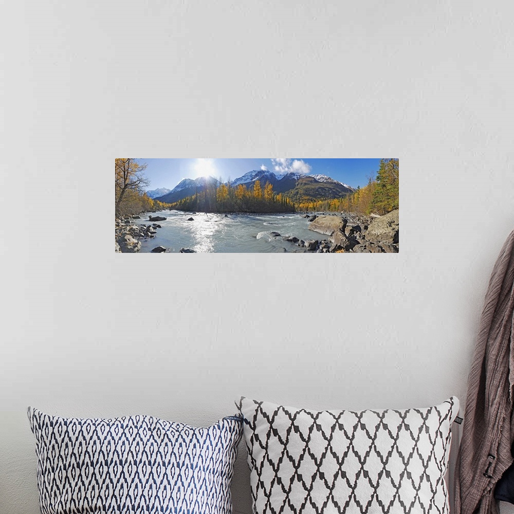 A bohemian room featuring A photograph of a river running through the Alaskan landscape in lined with trees on a sunny day ...
