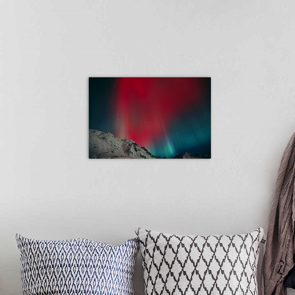 A bohemian room featuring Photo on canvas of an aurora in the night sky above snow covered rugged mountains.
