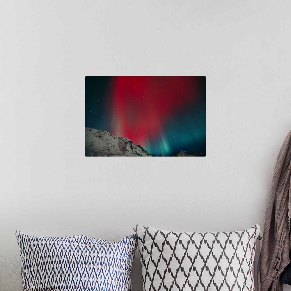 A bohemian room featuring Photo on canvas of an aurora in the night sky above snow covered rugged mountains.