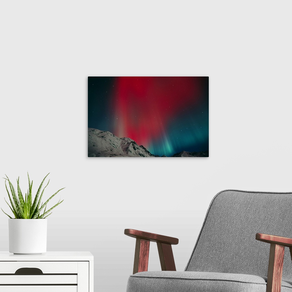 A modern room featuring Photo on canvas of an aurora in the night sky above snow covered rugged mountains.