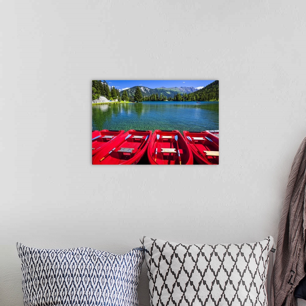 A bohemian room featuring Red boats lined up at Champex Lake under blue sky with a mountain range in the background; Champe...