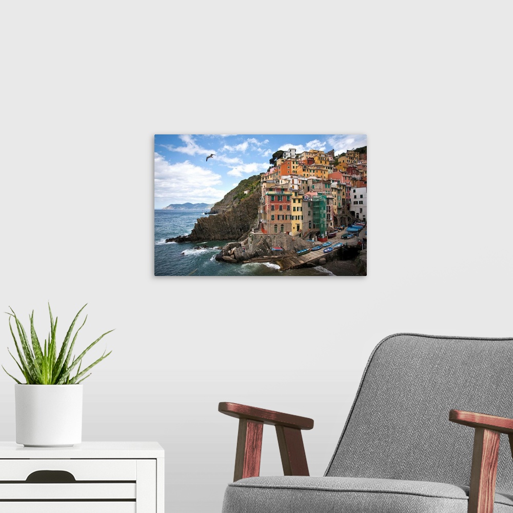 A modern room featuring Riomaggiore perched on an outcrop above the sea.