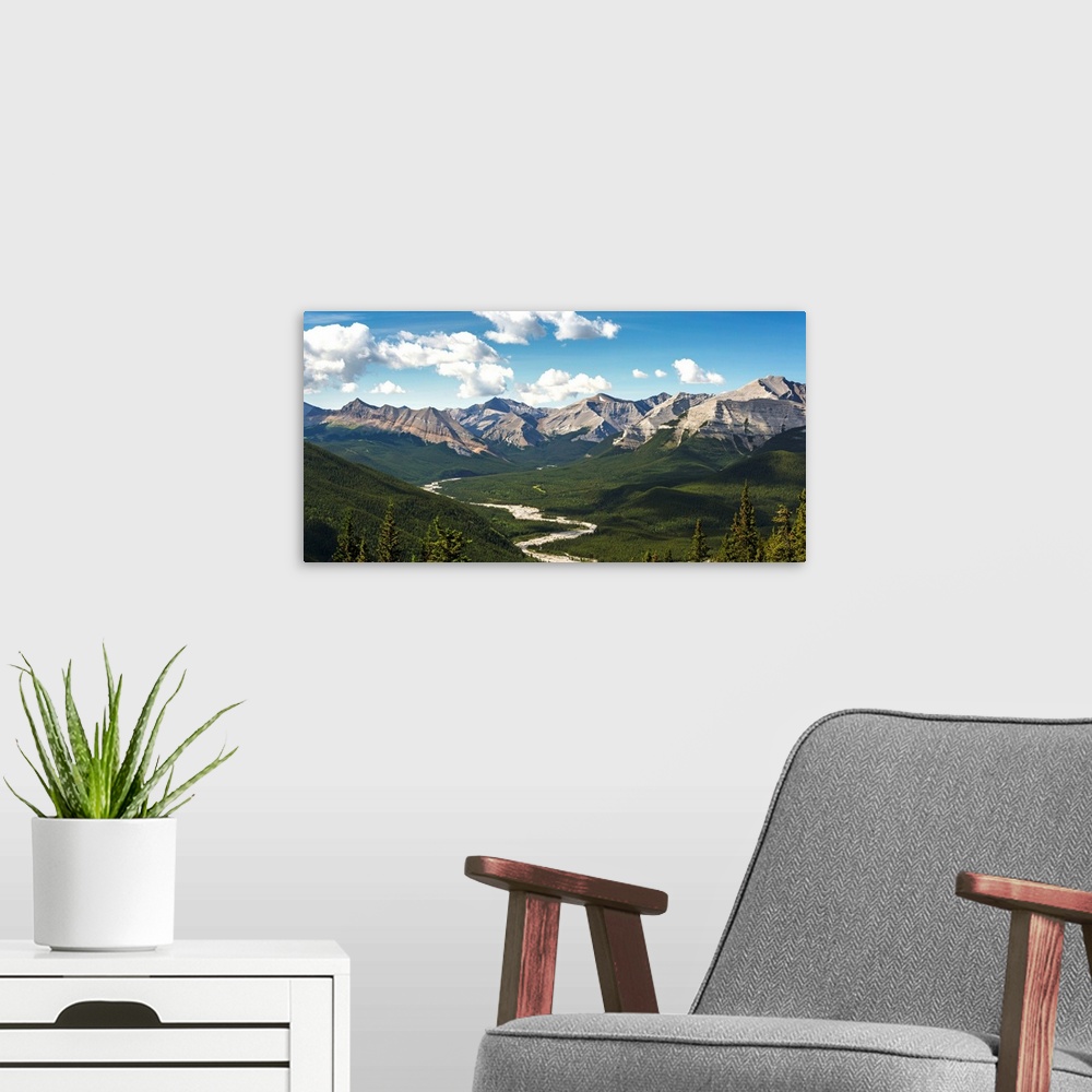 A modern room featuring Panorama of river valley and mountain range with blue sky and clouds, Bragg Creek, Alberta, Canada.