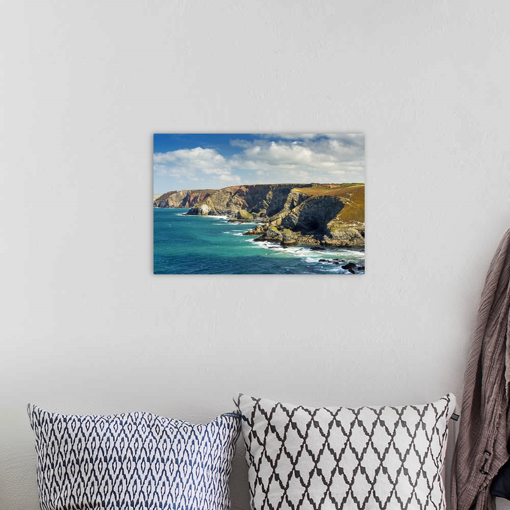 A bohemian room featuring Rocky cliffs along the shoreline with clouds and blue sky; Cornwall County, England.
