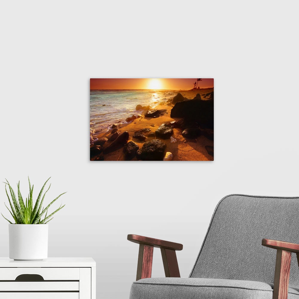 A modern room featuring Photograph taken of a sunset on the ocean horizon with various rocks spread out on the beach in t...