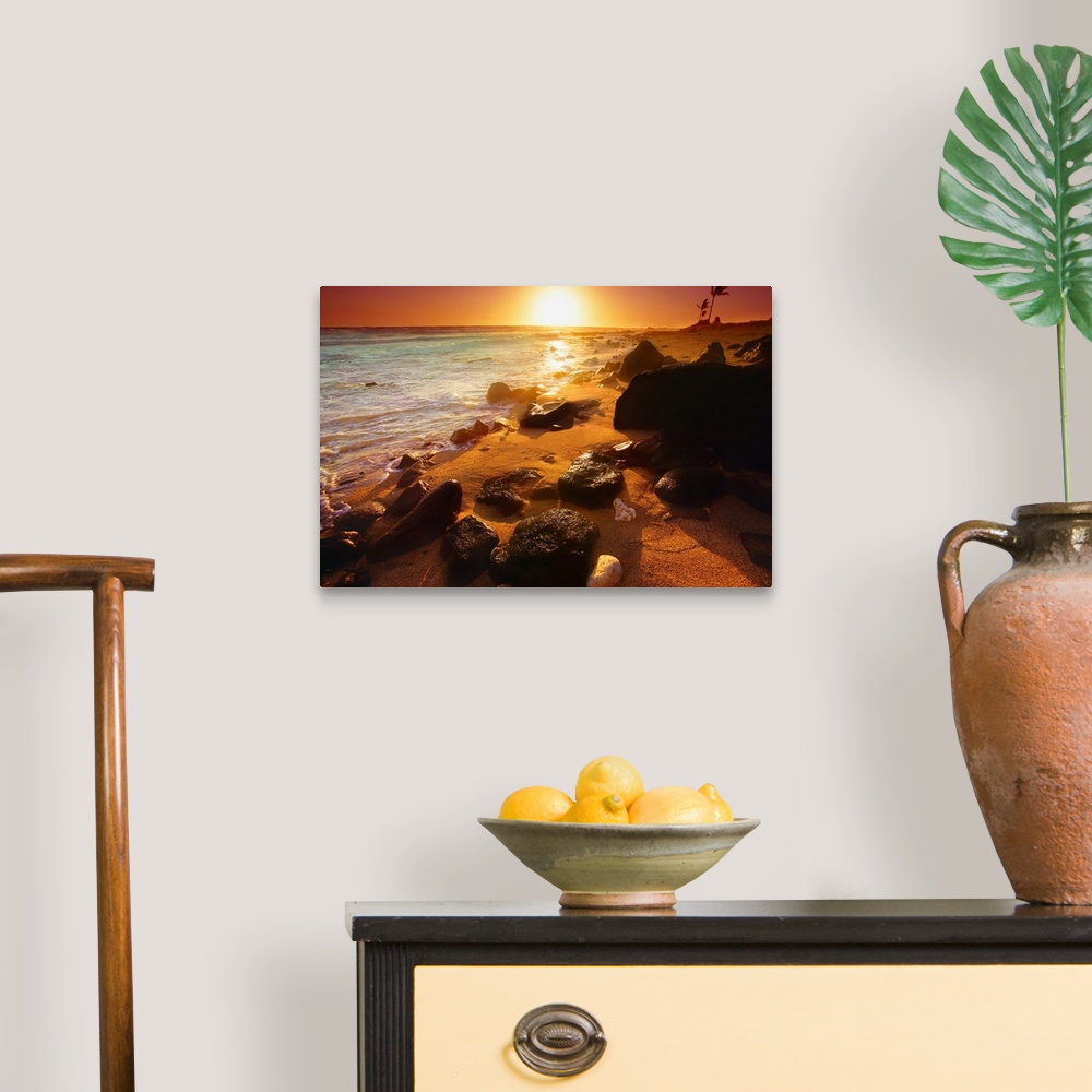A traditional room featuring Photograph taken of a sunset on the ocean horizon with various rocks spread out on the beach in t...