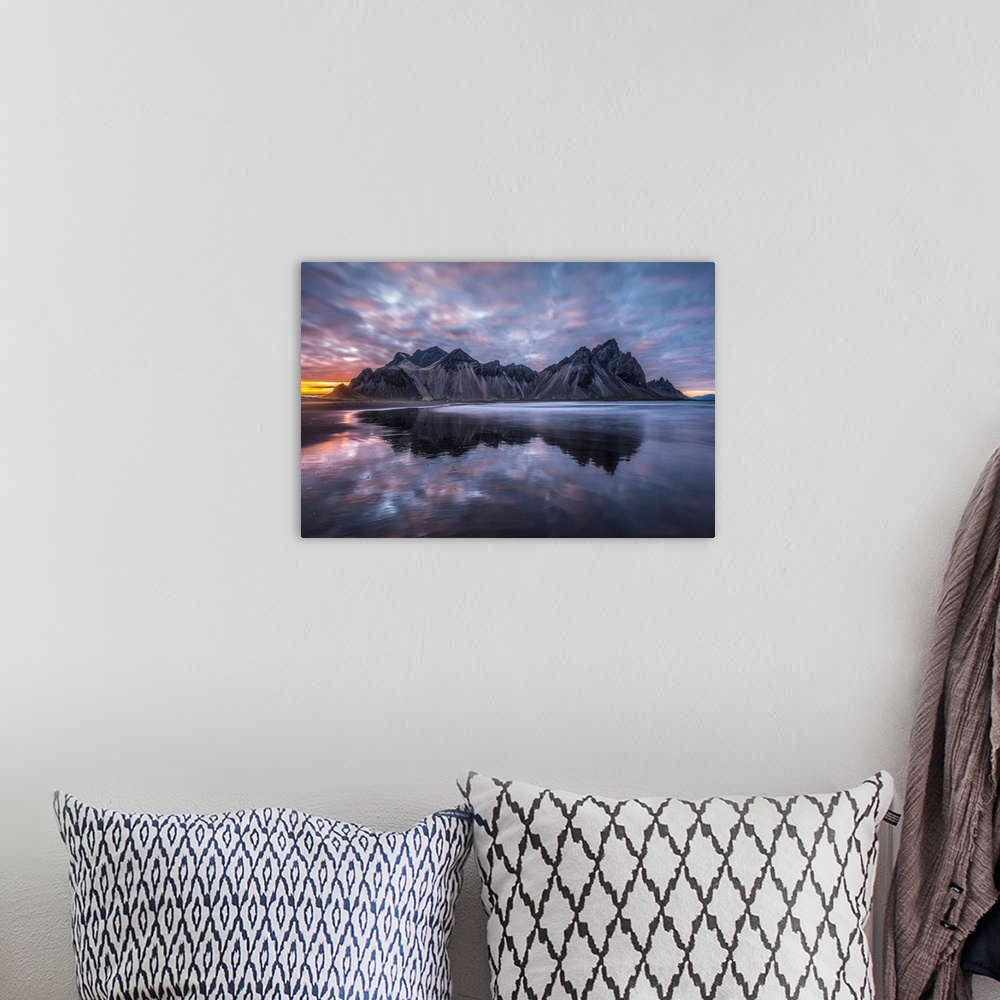 A bohemian room featuring Rugged mountain peaks and a colourful sunset reflected in tranquil water. Iceland.