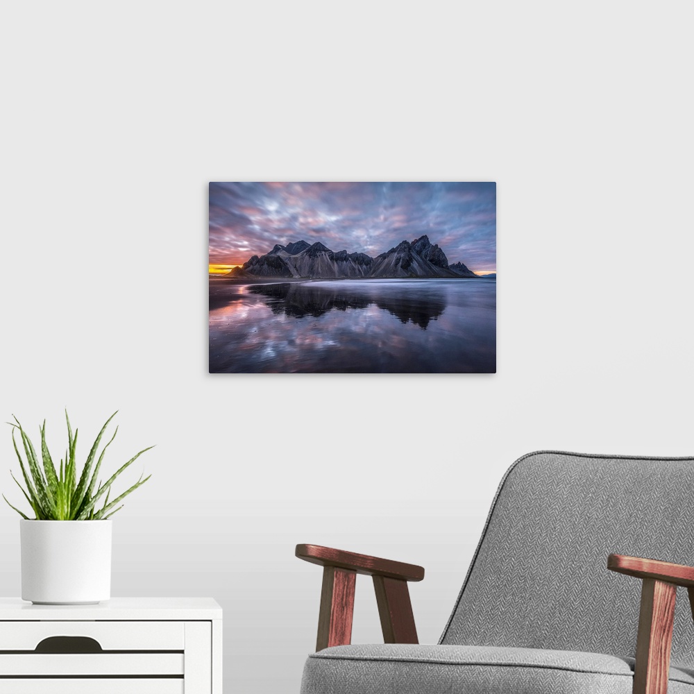 A modern room featuring Rugged mountain peaks and a colourful sunset reflected in tranquil water. Iceland.