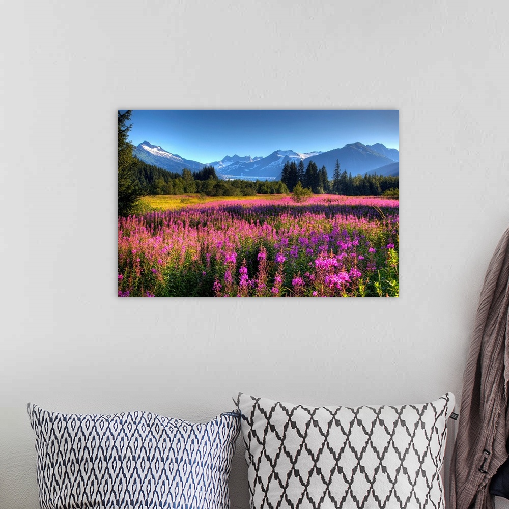 A bohemian room featuring Oversized wall art of a meadow of wildflowers in a valley of evergreen trees with an Alaskan glac...