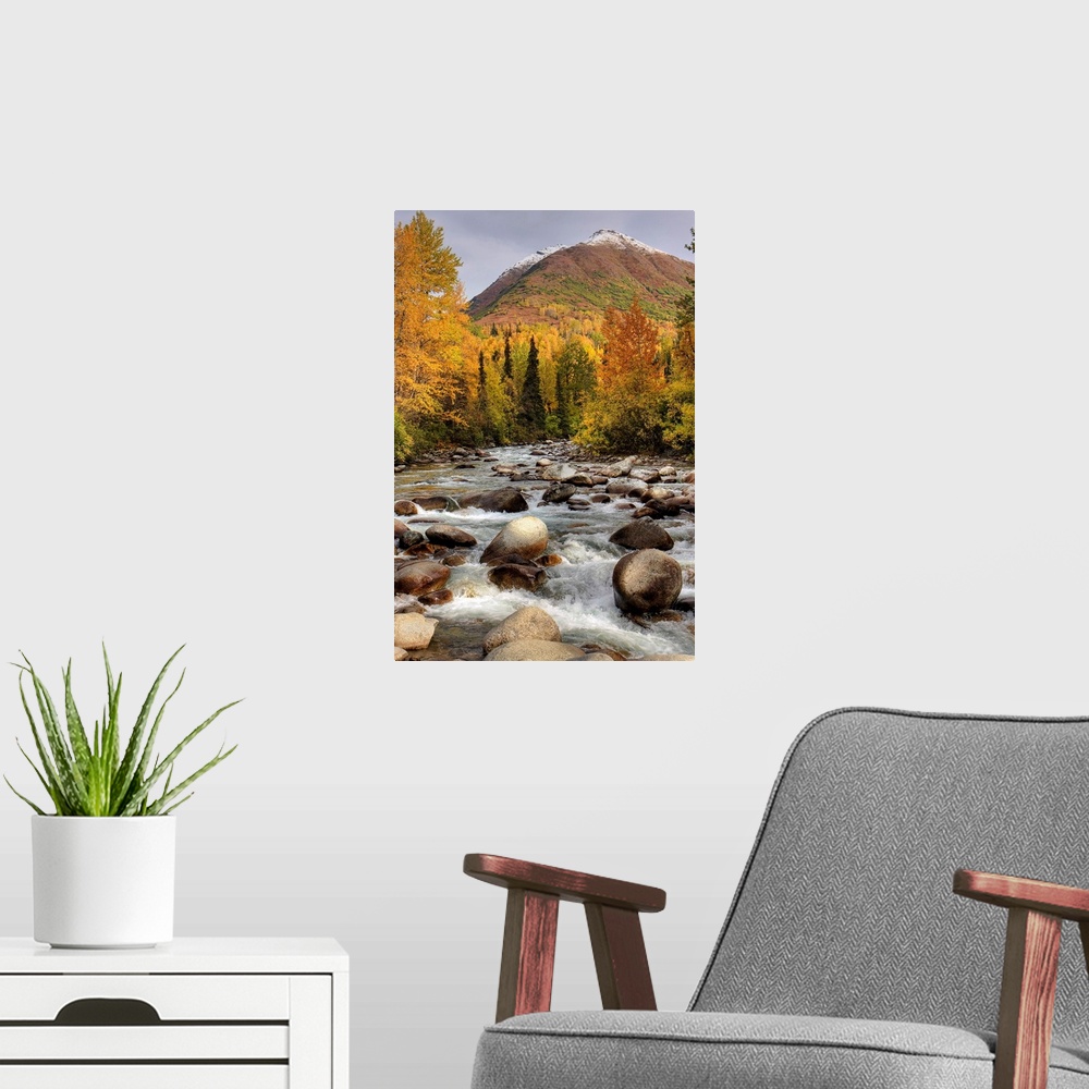 A modern room featuring Vertical photograph on a large wall hanging of the rocky Little Susitna River leading toward a la...