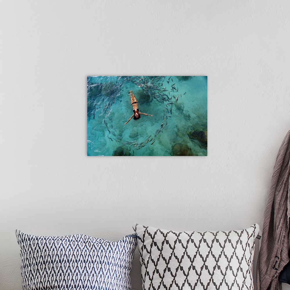 A bohemian room featuring School Of Fish Encircling Woman Floating In Tropical Ocean Water