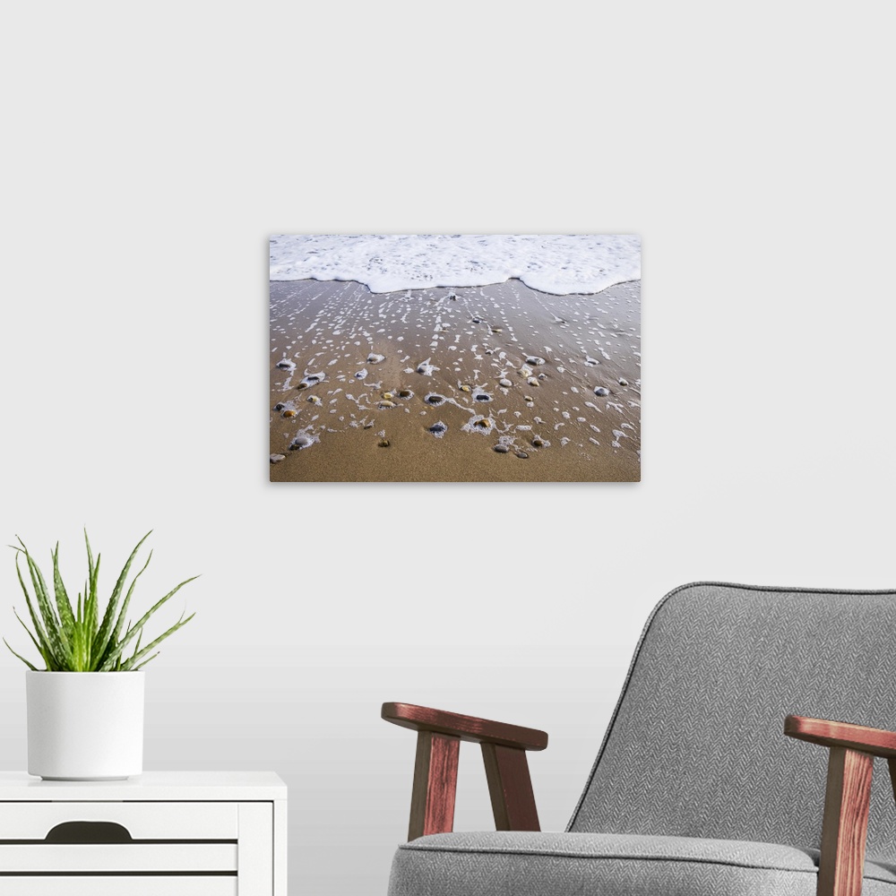 A modern room featuring Sea foam trails from beached pebbles as the tide is pulled out, south shields, Tyne and Wear, Eng...