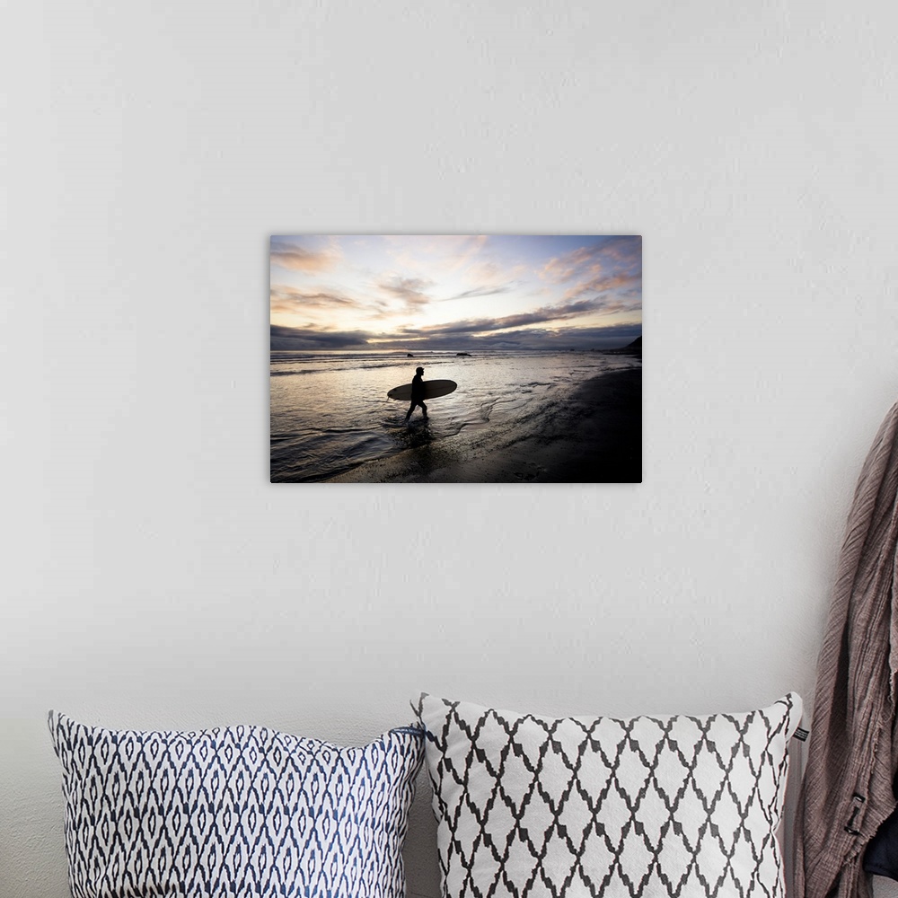 A bohemian room featuring Silhouette Of A Surfer Carrying A Surfboard Back To Shore At Sunset; Alaska, United States Of Ame...