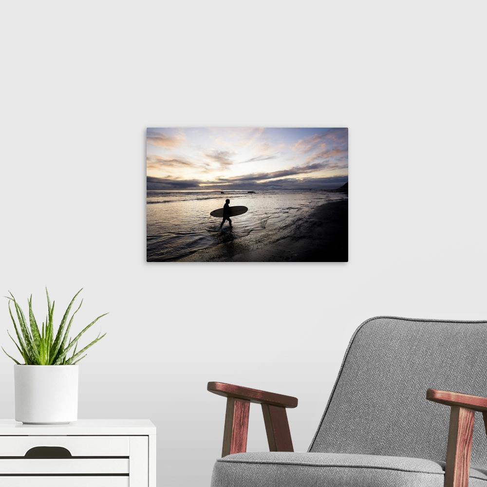 A modern room featuring Silhouette Of A Surfer Carrying A Surfboard Back To Shore At Sunset; Alaska, United States Of Ame...