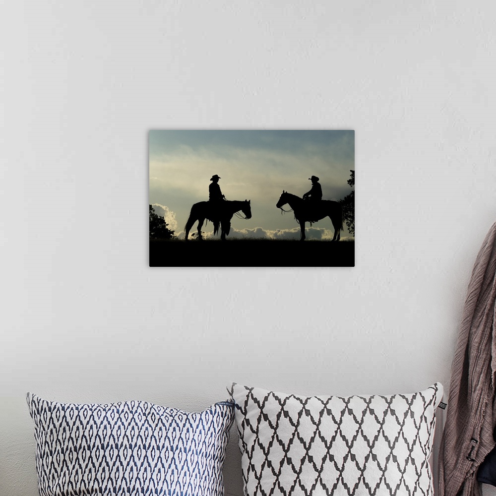 A bohemian room featuring Silhouette of two cowboys on horses against a cloudy sky; Montana, United States of America.