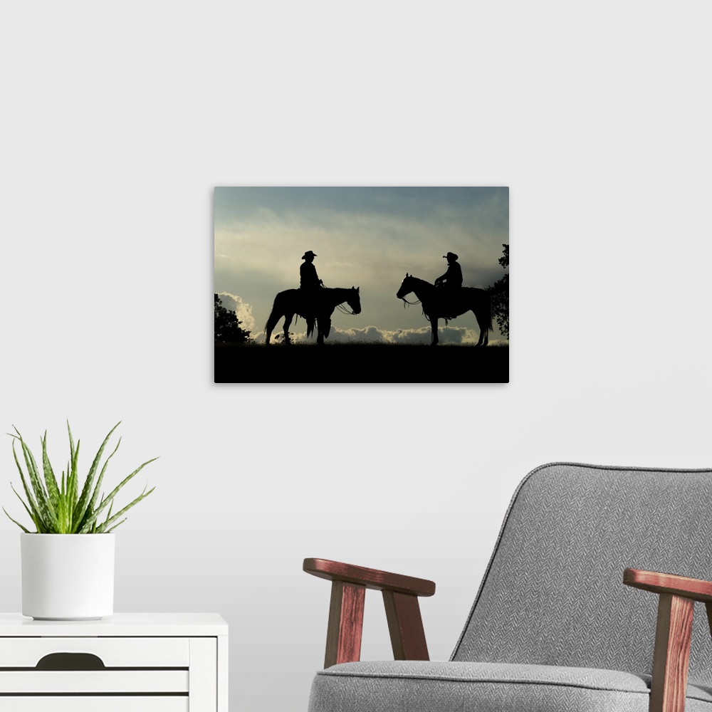 A modern room featuring Silhouette of two cowboys on horses against a cloudy sky; Montana, United States of America.