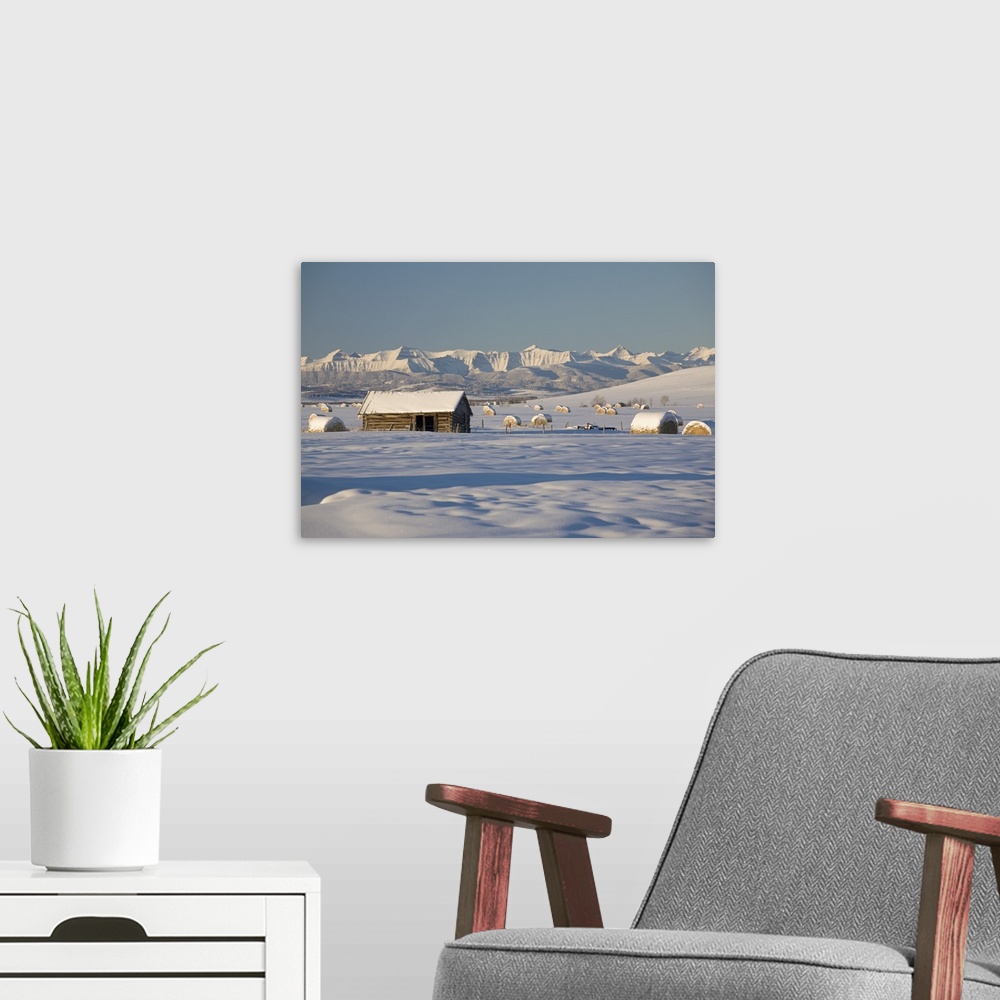 A modern room featuring Snow Covered Log Cabin With Snow Covered Mountains; Okotoks, Alberta, Canada