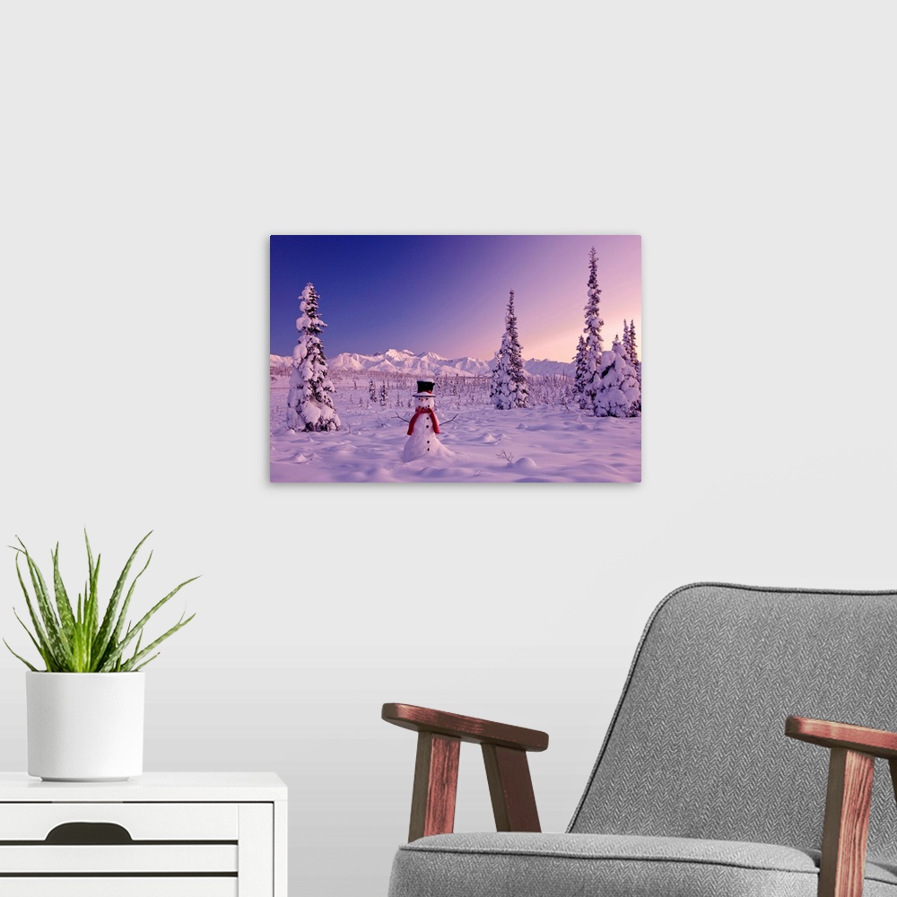 A modern room featuring Large canvas photo of a snowman sitting in a snowy landscape with mountains in the distance and s...