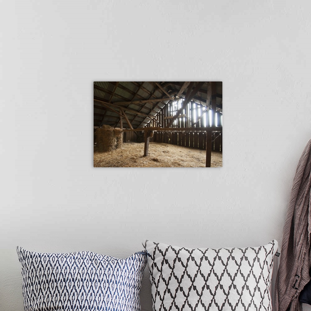A bohemian room featuring Sunlight filters through the sides of an old barn onto the stored hay