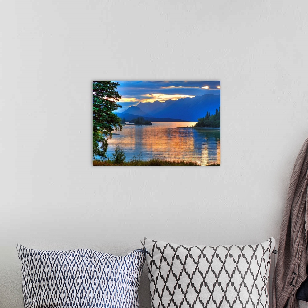 A bohemian room featuring A landscape photograph of morning light reflecting on a lake in the mountains surrounded by trees.