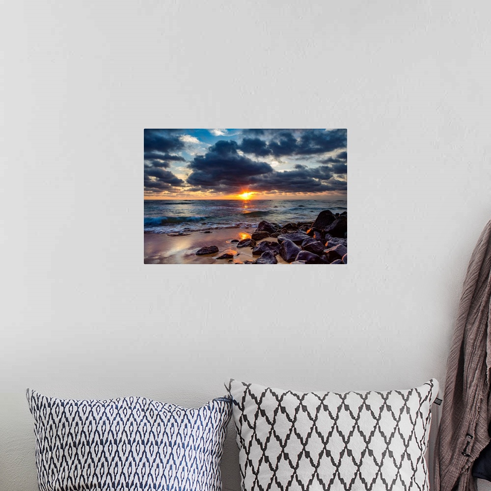 A bohemian room featuring Sunrise over the Pacific Ocean from the rocks on the shore of Lydgate beach and dark clouds overh...