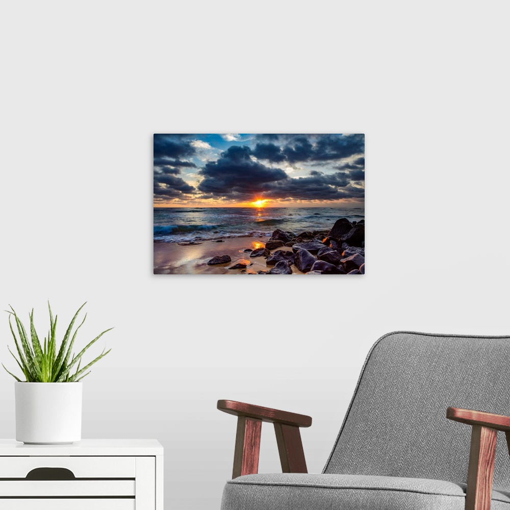 A modern room featuring Sunrise over the Pacific Ocean from the rocks on the shore of Lydgate beach and dark clouds overh...