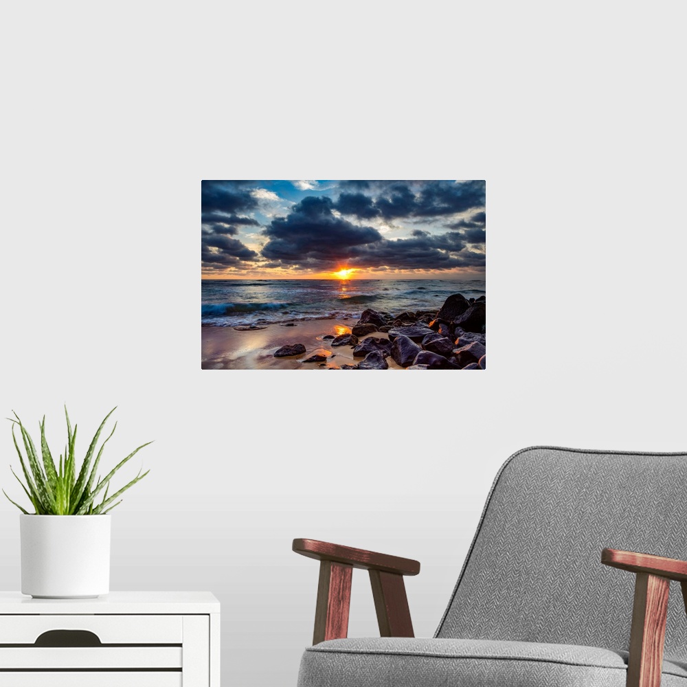 A modern room featuring Sunrise over the Pacific Ocean from the rocks on the shore of Lydgate beach and dark clouds overh...