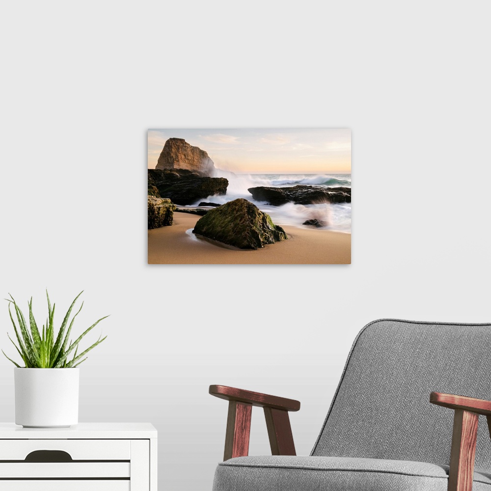A modern room featuring Sunset along the central California coast with waves crashing onto the large rocks on the beach S...