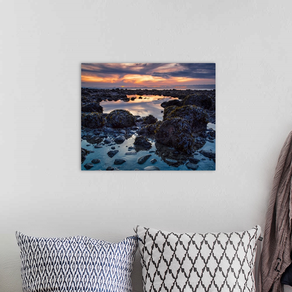A bohemian room featuring Warm colours from a sunset sky reflect in the tide pools on Acadia Beach; Vancouver, British Colu...