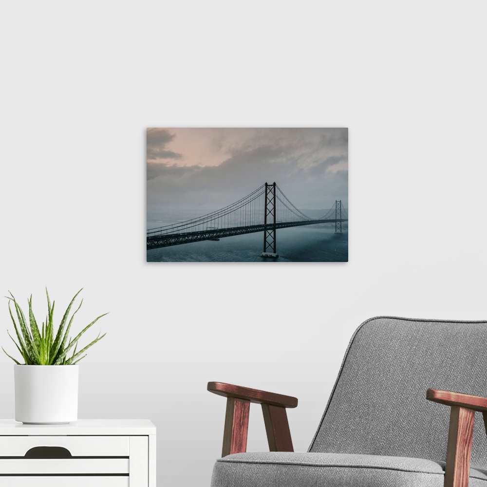 A modern room featuring The 25 de Abril Bridge crossing the Tagus River, connecting Lisbon and Almada on a grey, foggy da...