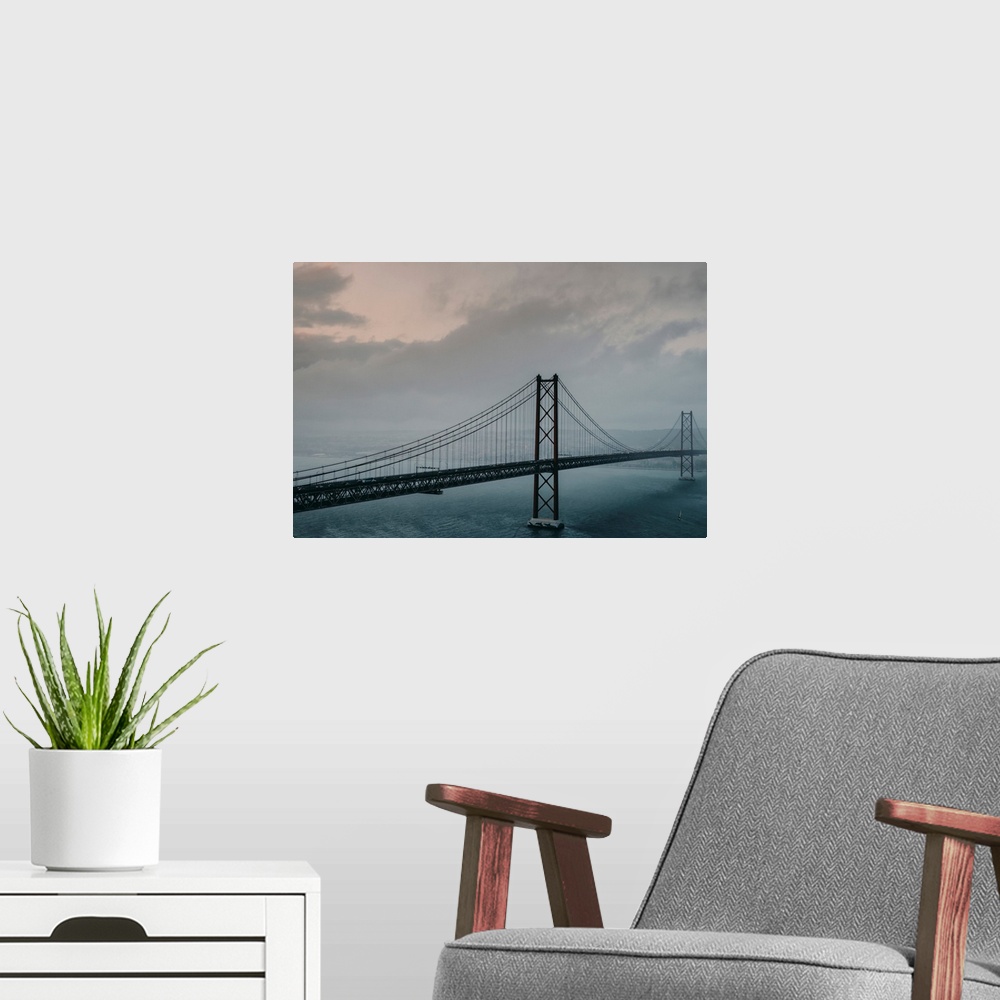 A modern room featuring The 25 de Abril Bridge crossing the Tagus River, connecting Lisbon and Almada on a grey, foggy da...