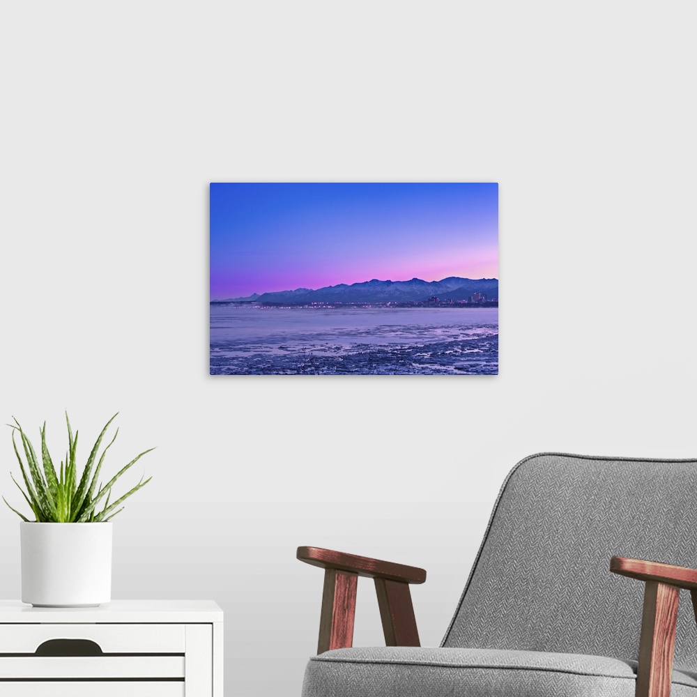 A modern room featuring The Anchorage Skyline before dawn with fog rising from the waters of Knik Arm as seen from Earthq...