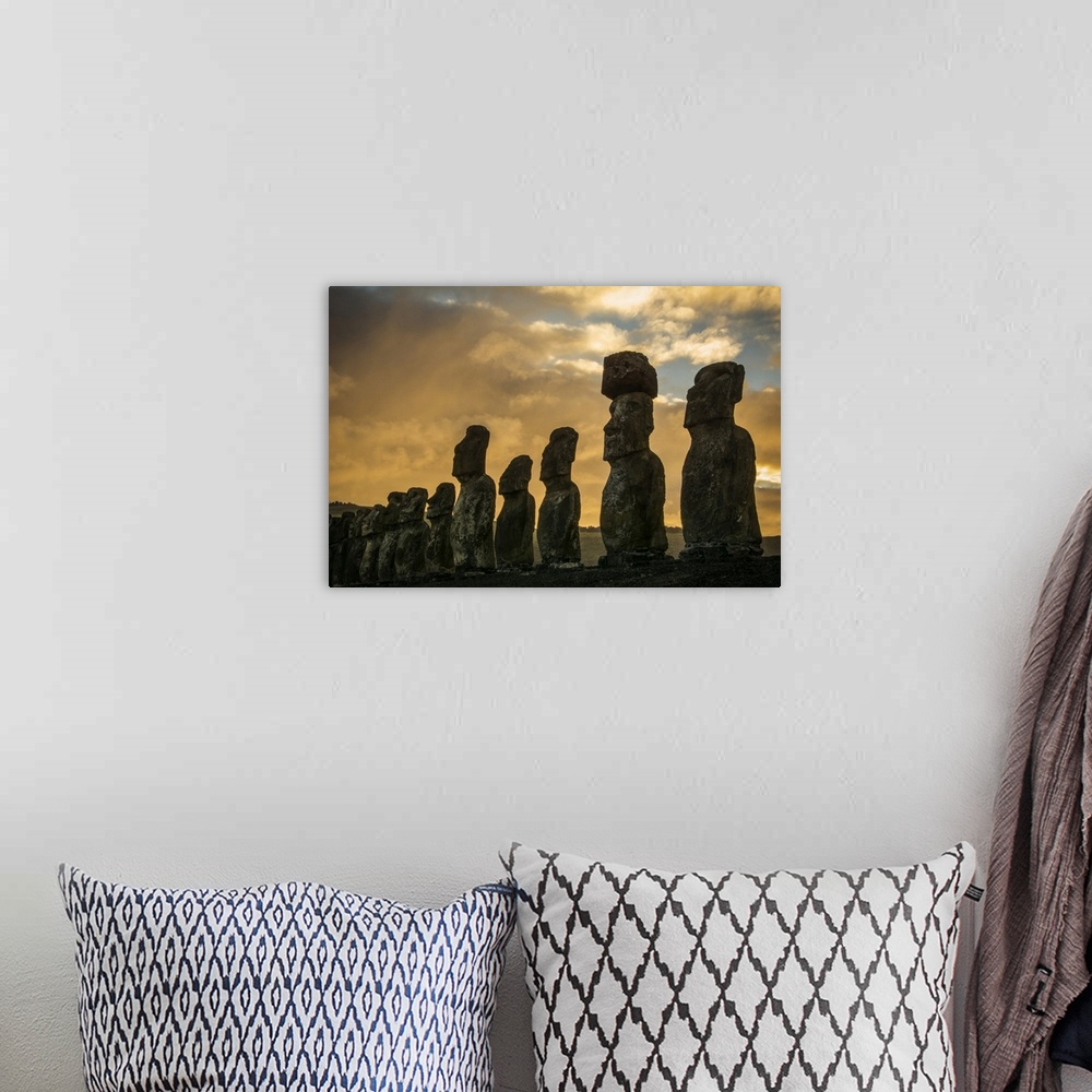 A bohemian room featuring The fifteen moais of Tongariki close-up in decreasing perspective against a colourful sunrise; Ea...