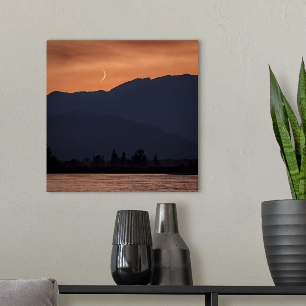 A modern room featuring The moon and Venus in an orange sky over the silhouetted mountains, Fraser Valley; Vancouver, Bri...