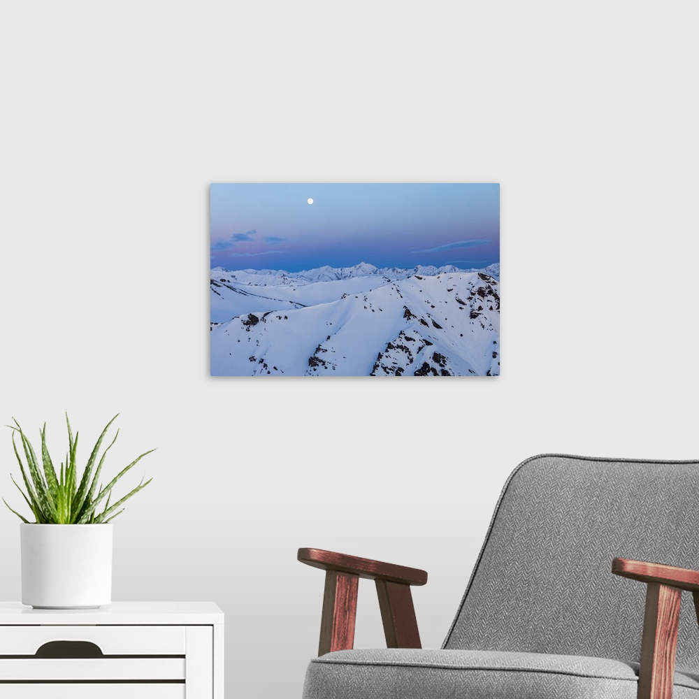 A modern room featuring The moon rises over snowy mountain ridges after sunset in the Alaska Range; Alaska, United States...