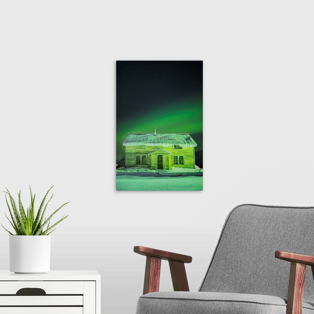 A modern room featuring The Northern Lights in the sky above 'Our Lady of the Snows' Catholic Mission Building in winter,...