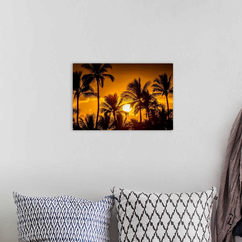 A bohemian room featuring The sun setting through silhouetted palm trees; Wailea, Maui, Hawaii, United States of America.