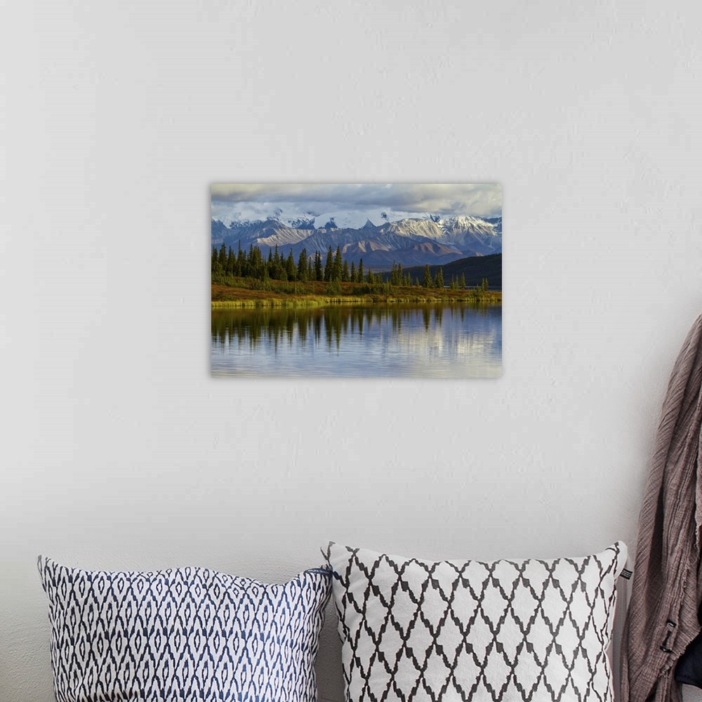 A bohemian room featuring Trees reflected in the surface of Wonder Lake in Denali National Park.