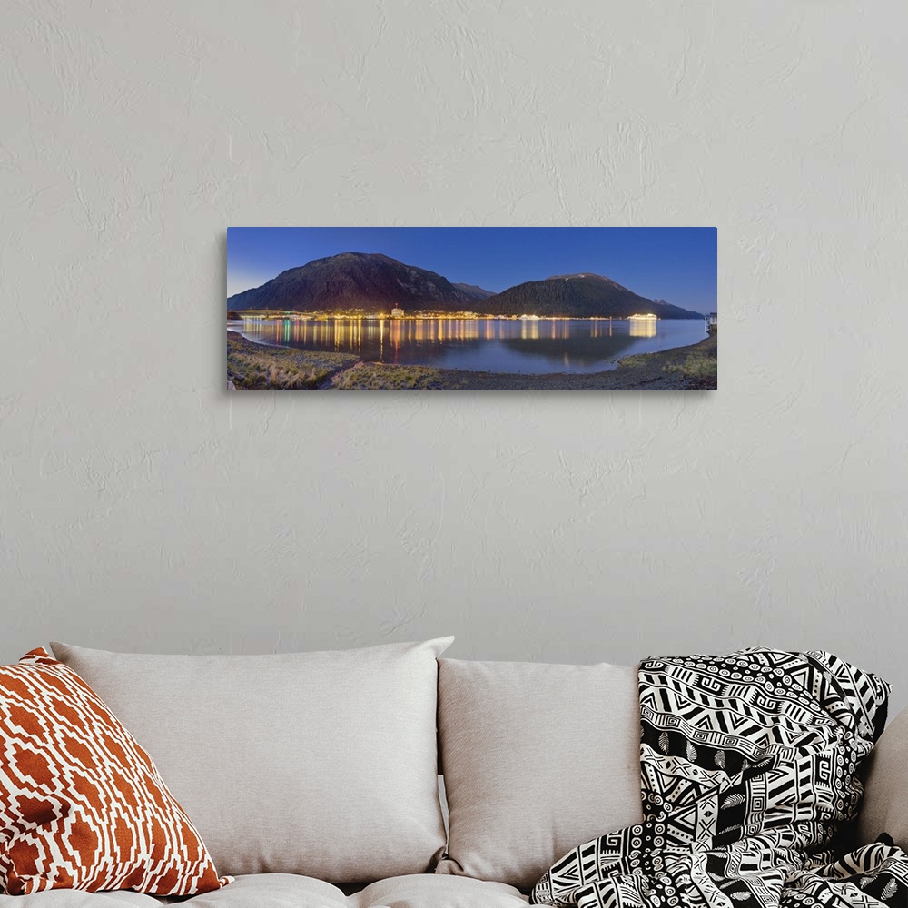 A bohemian room featuring Downtown Juneau photographed across the water from Douglas Island, city lights reflected in the w...