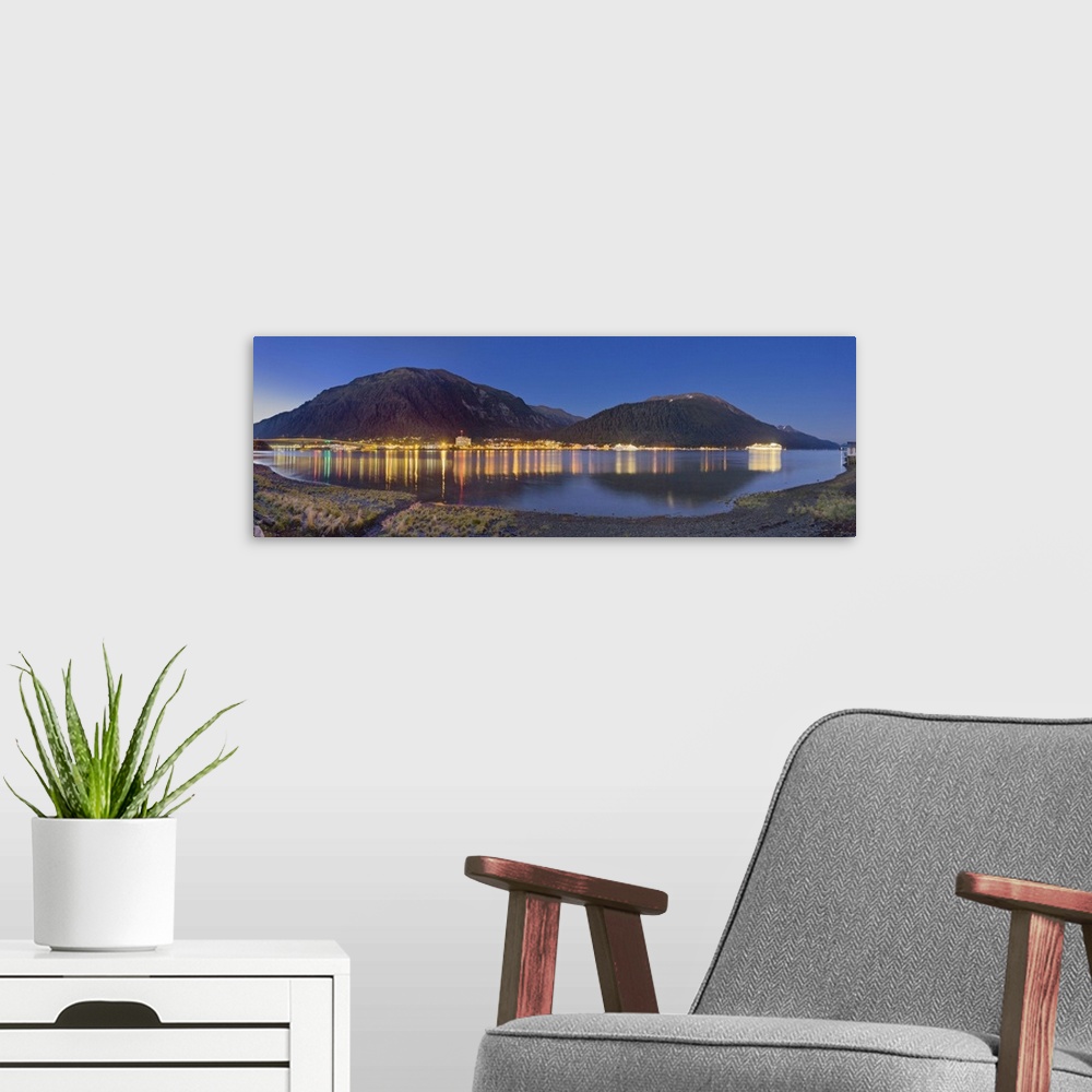 A modern room featuring Downtown Juneau photographed across the water from Douglas Island, city lights reflected in the w...