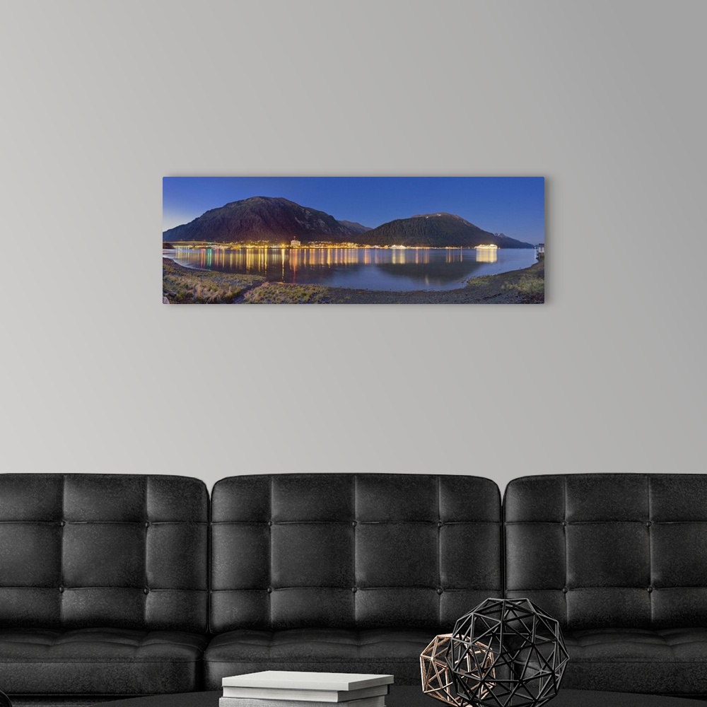 A modern room featuring Downtown Juneau photographed across the water from Douglas Island, city lights reflected in the w...