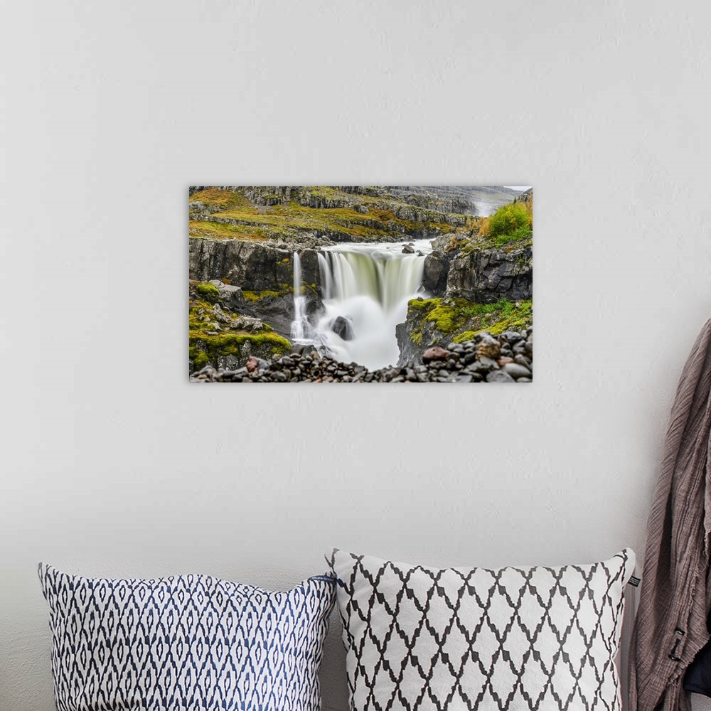 A bohemian room featuring A waterfall over a rocky landscape in autumn colours; Djupivogur, Eastern Region, Iceland.