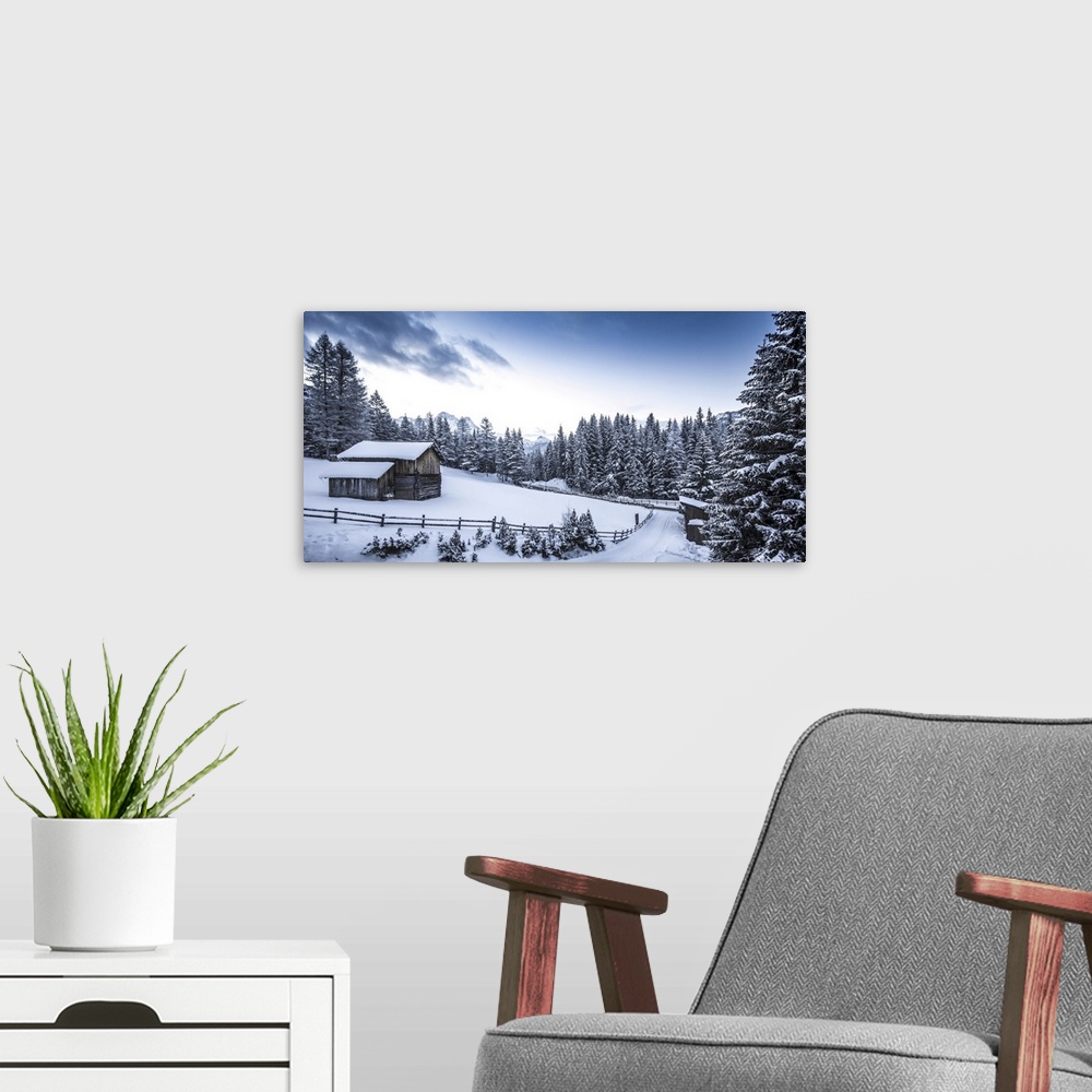 A modern room featuring Winter scene looking down a country road at a log cabin surrounded by snow covered pine trees in ...
