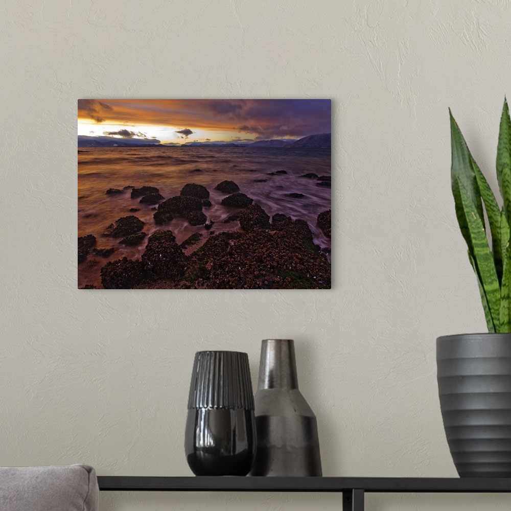 A modern room featuring The view North over Zimovia Strait from Petroglyph Beach at sunset as small waves move over the b...