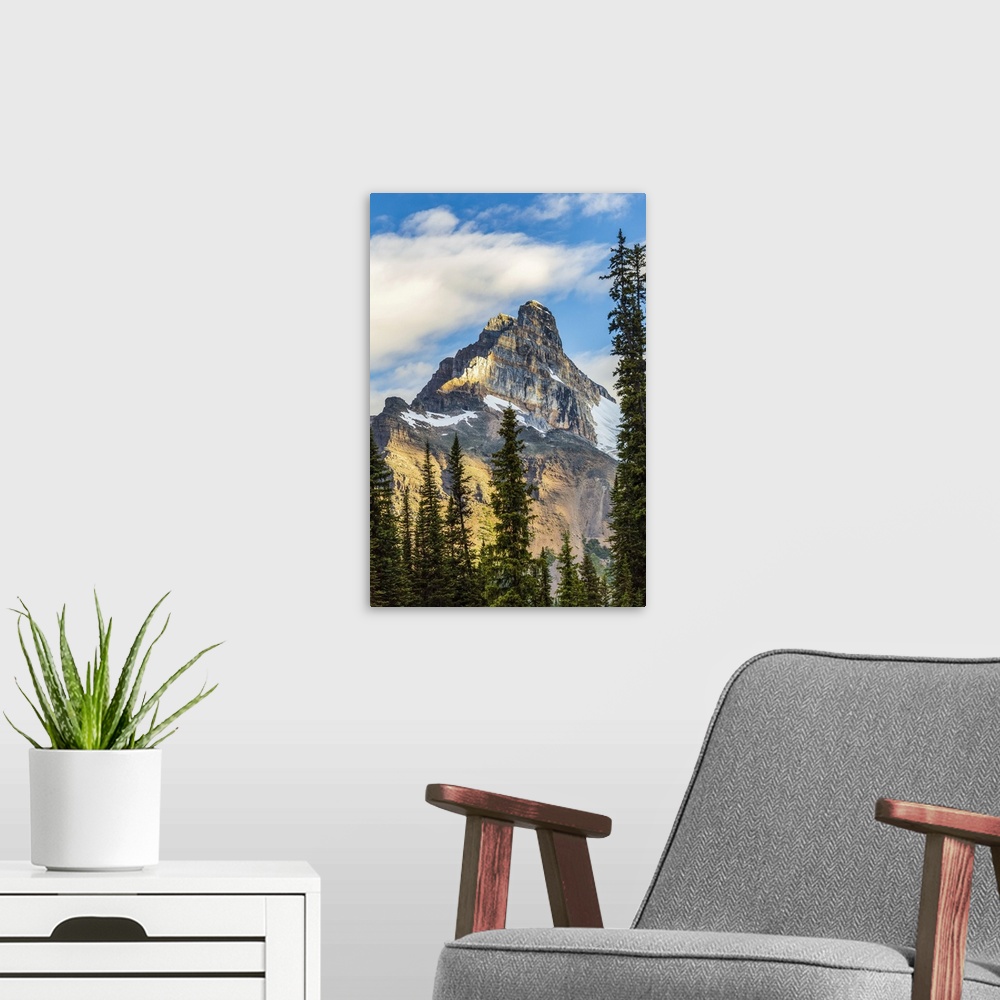 A modern room featuring Mountain cliff peak dramatically lit by the sun with blue sky and clouds, Yoho National Park; Fie...