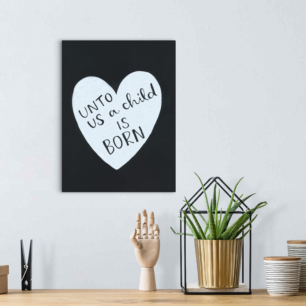 A bohemian room featuring The text "Unto us a child is born" handwritten inside a heart shape on a dark background.