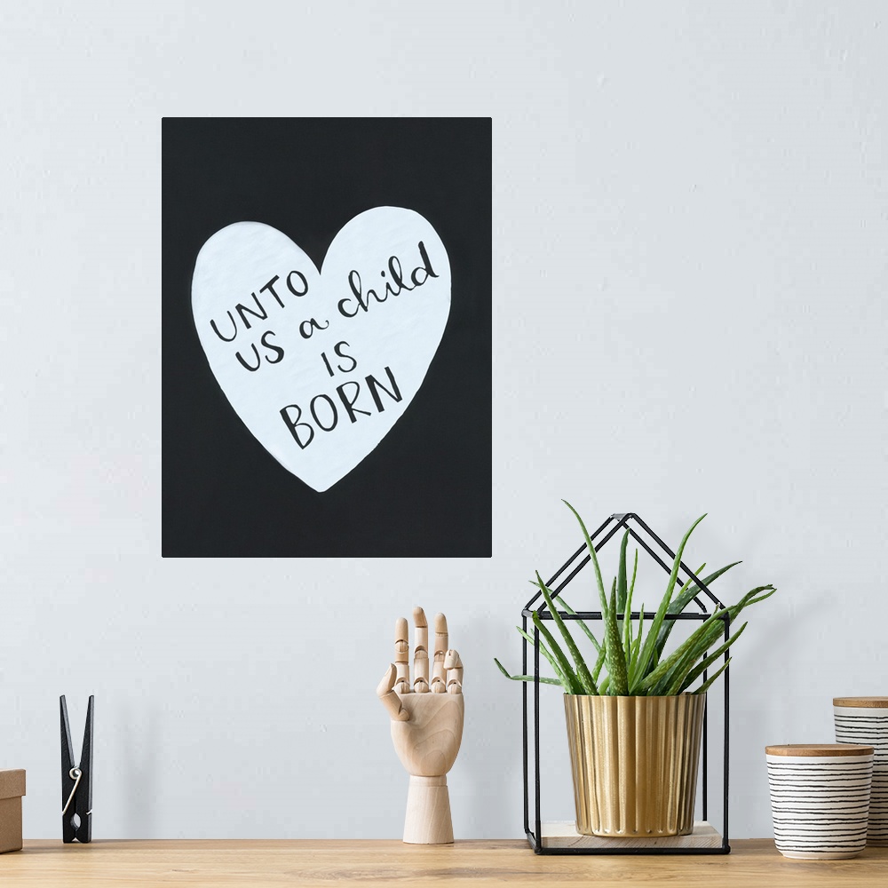 A bohemian room featuring The text "Unto us a child is born" handwritten inside a heart shape on a dark background.