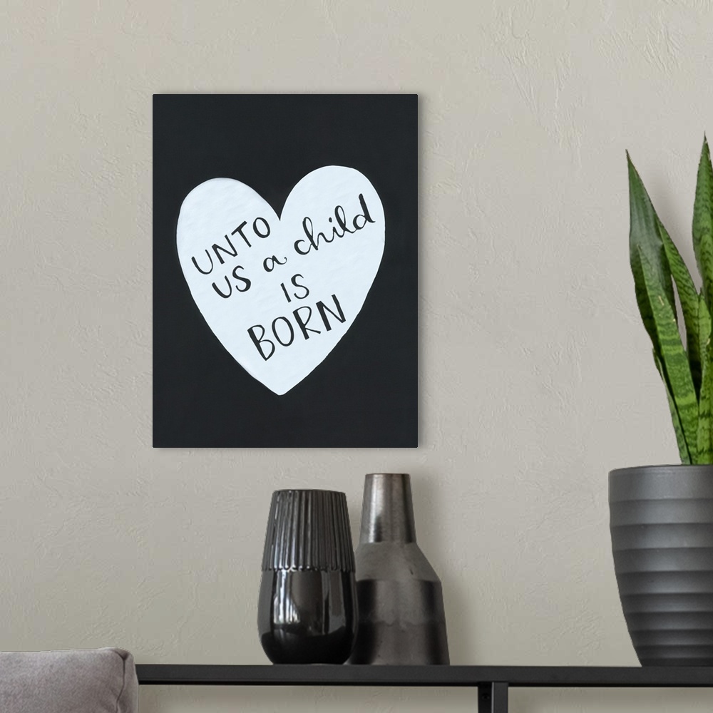 A modern room featuring The text "Unto us a child is born" handwritten inside a heart shape on a dark background.